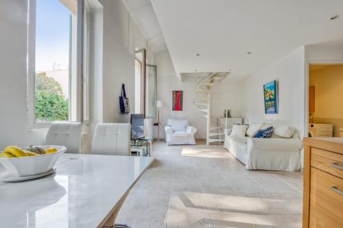 un salon avec des meubles blancs et une grande fenêtre dans l'établissement Magnifique appartement proche de la plage au coeur de Cannes - Welkeys, à Cannes