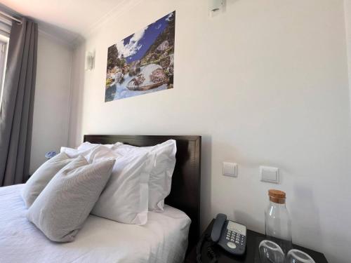 a bedroom with a bed with white pillows and a telephone at Vale do Zêzere Hotel in Manteigas