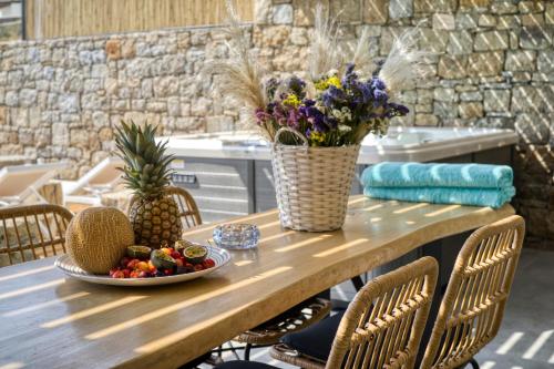 a table with a plate of fruit and flowers on it at Nefeli Residence & Suite Ftelia beach Mykonos in Elia