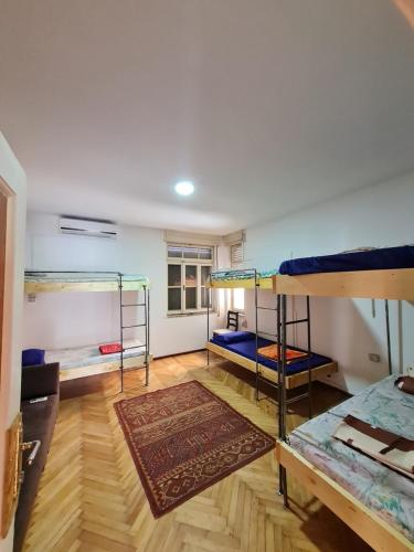 a room with three bunk beds and a rug at Milingona City Center Hostel in Tirana
