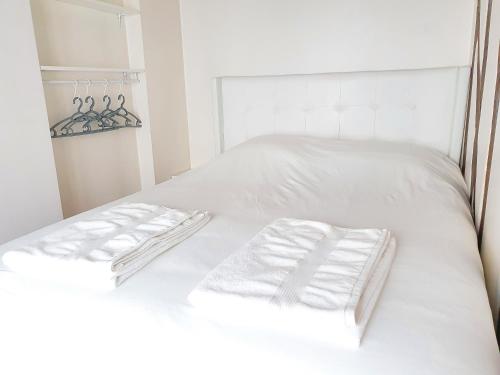 - un lit blanc avec 2 serviettes blanches dans l'établissement EXIGEHOME-Studio Cosy à 2 pas du Chateau de Versailles, à Versailles