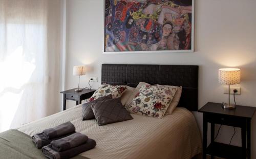 Un dormitorio con una cama con almohadas y una pintura en Butiplaya apartament, en La Cala de Mijas
