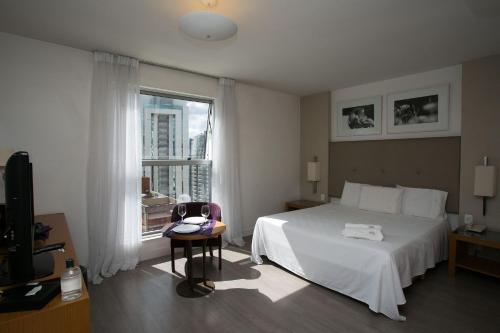 um quarto com uma cama branca e uma janela em Locking's Santo Agostinho 9 em Belo Horizonte