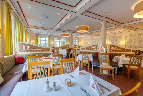 a dining room with white tables and chairs at Berghotel Hammersbach in Grainau