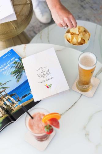 a table with a book and a drink and chips at Best Western Hotel Mediterranee Menton in Menton