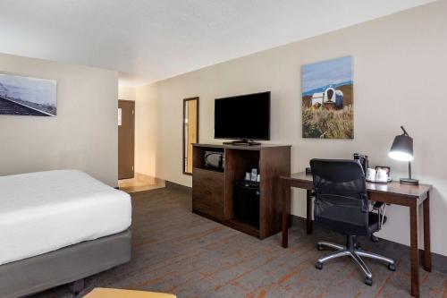a hotel room with a bed and a desk with a television at Best Western Sunridge Inn & Conference Center in Baker City