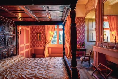 ein Schlafzimmer mit einem Himmelbett und einem Schreibtisch in der Unterkunft Château de La Vigne in Ally
