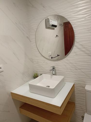 a white bathroom with a sink and a mirror at Apartamento Playa de Covas in Viveiro