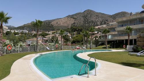 una piscina en un complejo con montañas en el fondo en Lovely 2-Bedroom Holiday Home Higuerón Area, en Málaga