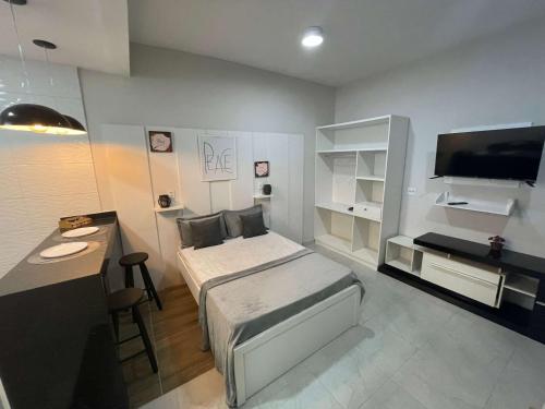 Central Praias Suite 1 في كابو فريو: غرفة بسرير ومكتب وتلفزيون