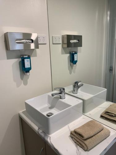 a bathroom with a sink, mirror, and towel dispenser at Adina Place Motel Apartments in Launceston