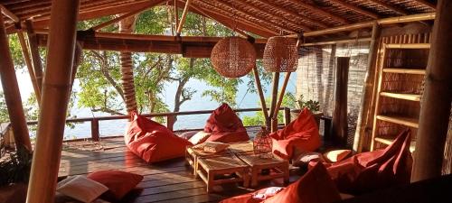 una sala de estar con almohadas rojas en el porche en Tanjungan, en Gili Gede