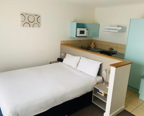 a hotel room with a bed and a microwave at Adina Place Motel Apartments in Launceston