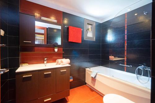 a bathroom with a tub and a sink and a bath tub at Villa Rubi by Villa Plus in Karavomylos