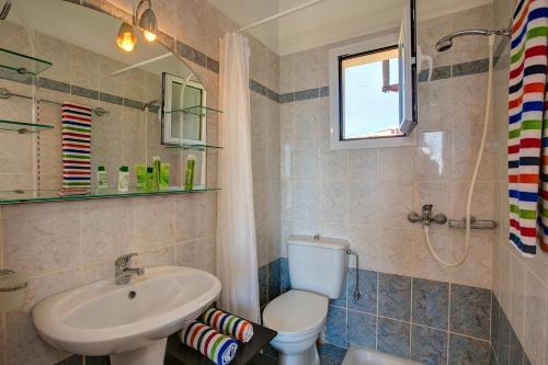 a bathroom with a white toilet and a sink at Villa Skala Beachview by Villa Plus in Spathíon