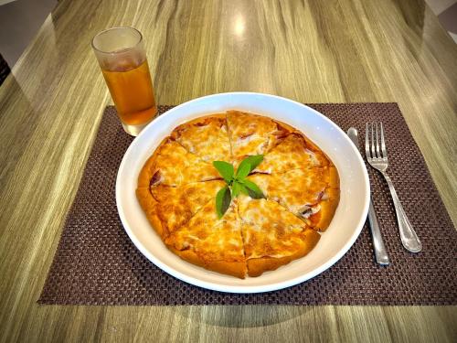 a pizza on a plate on a table with a drink at Sea Passion Hotel in Koror