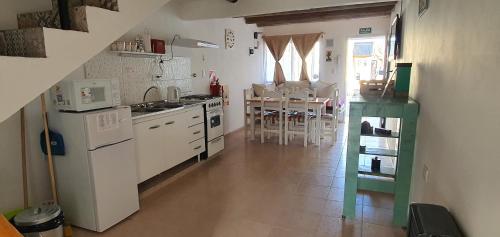 a kitchen with white appliances and a table with chairs at LOS CACTUS in Malargüe