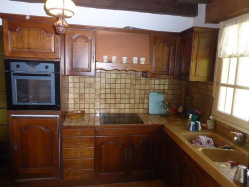 une cuisine avec des armoires en bois et un four à plaques de cuisson dans l'établissement Maison Pieds dans l'Eau avec Grand Jardin, 3 Chambres, Animaux Acceptés - FR-1-397-21, à Locoal