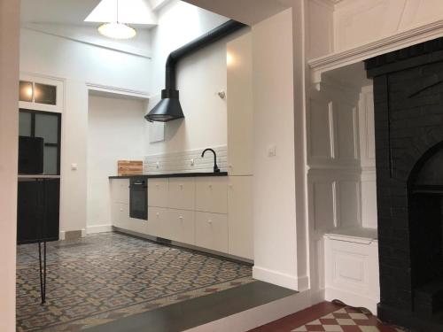 - une cuisine avec des murs blancs et un poêle noir dans l'établissement Gîte rénové de charme avec parc, étang, proche de Paris et Versailles - FR-1-527-11, à Senlisse