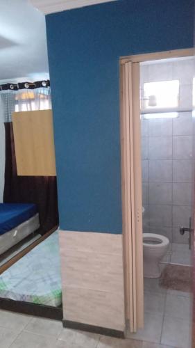 a bathroom with a toilet and a blue wall at Quartos ao Lado Expominas in Belo Horizonte