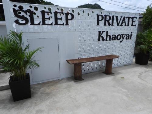 a wooden bench sitting in front of a sign at Sleep private khaoyai in Mu Si