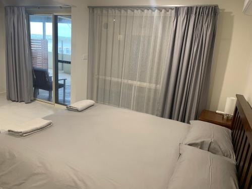 a bedroom with a large white bed and a window at Beachside & Jetty View Apartment 4 - First Mate Apt limited sea view in Streaky Bay