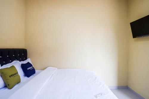 a bedroom with a white bed with two pillows at Urbanview Hotel Telu Wolu Monjali by RedDoorz in Kejayan