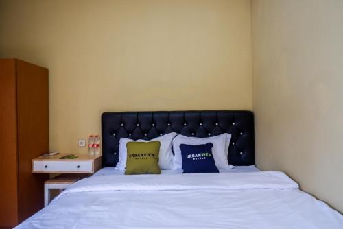 a bedroom with a bed with blue and yellow pillows at Urbanview Hotel Telu Wolu Monjali by RedDoorz in Kejayan