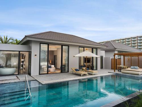 a house with a swimming pool next to a house at Crowne Plaza Phu Quoc Starbay by IHG in Phu Quoc
