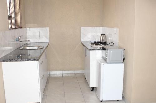 a small kitchen with a sink and a refrigerator at Unit G Guest House in Ga-Mothiba