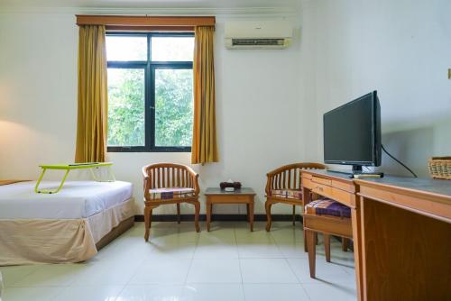 a hotel room with a bed and a television at Urbanview by Millenium Hotel in Pangkalpinang