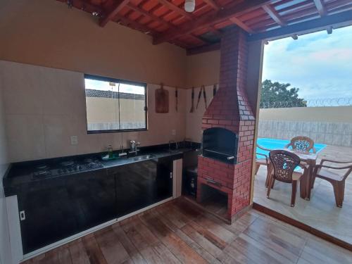 eine Küche mit einem gemauerten Kamin und einem Tisch mit Stühlen in der Unterkunft Casa linda caldas novas in Caldas Novas