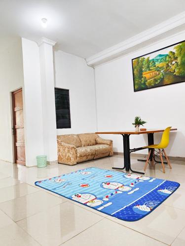a living room with a table and a blue rug at Homey Guesthouse Kertajaya (Syariah) in Surabaya