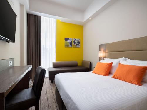 a hotel room with a bed and a desk and a chair at Hotel Traveltine in Singapore