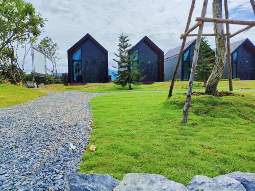a building with a tree next to a gravel road at ก๋างโต้ง คอฟฟี่รีสอร์ท in Ban Na Kham