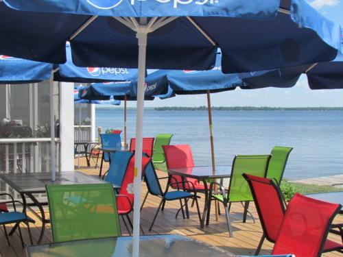 a group of tables and chairs under an umbrella at Lakeside Resort & Conference Center in Houghton Lake