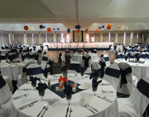 a large banquet hall with white tables and chairs at Lakeside Resort & Conference Center in Houghton Lake