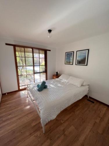 a bedroom with a white bed with a wooden floor at Palm Waters 4 - Wi-Fi & Linen Included in Inverloch