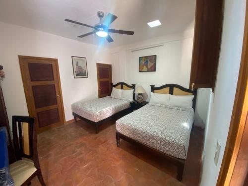 a room with two beds and a ceiling fan at Hotel del Sol in San Miguel de Allende