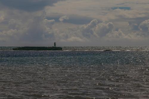 a man standing on an island in the ocean at Pousada Dunas do Icarai in Icaraí