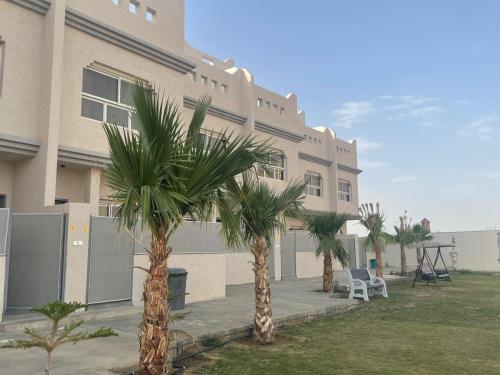 un bâtiment avec des palmiers en face de celui-ci dans l'établissement فلل السيف الخاصة, à Abha