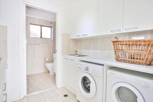 a white laundry room with a washer and dryer at Watermans Pet Friendly 1 Min Walk to Beach in Culburra Beach