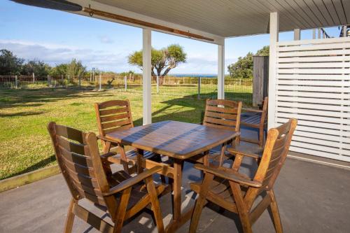 a wooden table and chairs on a patio at Watermans Pet Friendly 1 Min Walk to Beach in Culburra Beach