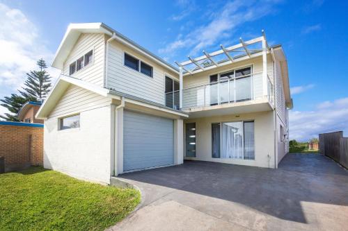 a large white house with a garage at Watermans Pet Friendly 1 Min Walk to Beach in Culburra Beach