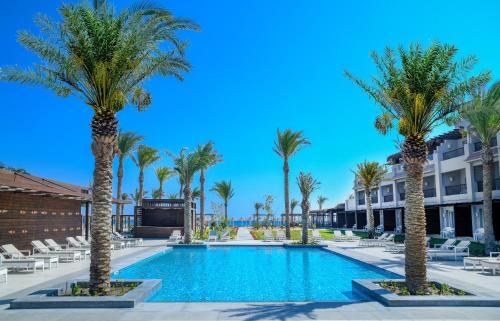 un complejo con piscina con palmeras y tumbonas en IBEROTEL Costa Mares en Marsa Alam