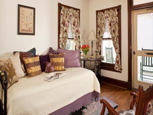 a bedroom with a bed and a table and windows at Brickhouse Inn B&B in Gettysburg