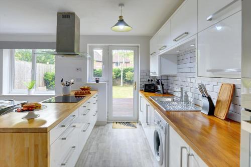 a kitchen with white cabinets and wooden counter tops at The Bernstein House 'Green Award' A Calm & Beautiful Executive House I Spacious Garden w Furniture I Parking I eco-Short Term Let by SILVA in Milton Keynes