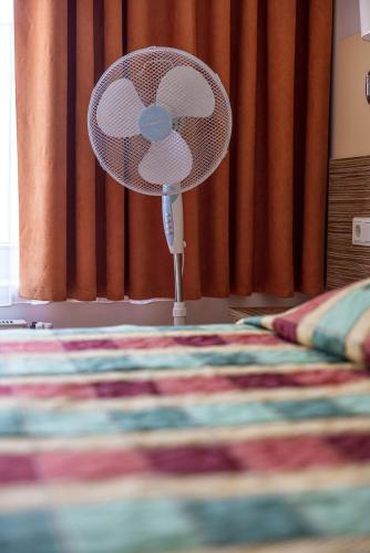 a fan sitting on the floor next to a bed at Info Hotel in Palanga