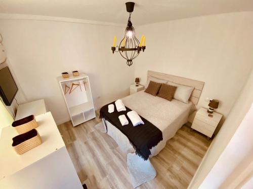 a white bedroom with a bed and a chandelier at Mirador del Atlántico in El Rompido