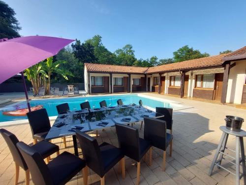 a dining table with chairs and an umbrella next to a pool at la dolce farniente in Biaudos